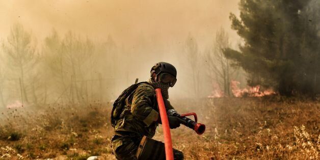 A firefighter works to extinguish a fire east of the Greek capital Athens on August 15, 2017. The army was called in to assist firefighters around Kalamos, 45 kilometres (30 miles) east of Athens, where a fire has been burning since August 13. In all, 146 fires have broken out across Greece since then according to authorities. / AFP PHOTO / ARIS MESSINIS (Photo credit should read ARIS MESSINIS/AFP/Getty Images)