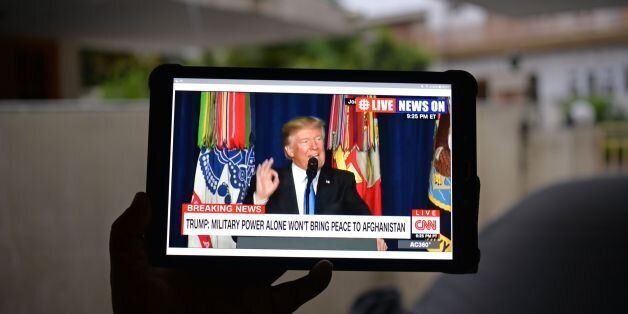 A Pakistani resident watches his tablet device in Islamabad on August 22, 2017,showing a live broadcast of US President Donald Trump delivering his address from Joint Base Myer-Henderson Hall in Arlington, Virginia in the US. President Donald Trump warned Pakistan that Washington will no longer tolerate Pakistan offering 'safe havens' to extremists. Trump suggested that military and other aid to Washington's nuclear-armed ally is at stake if it does not clamp down on extremism. / AFP PHOTO / AAM