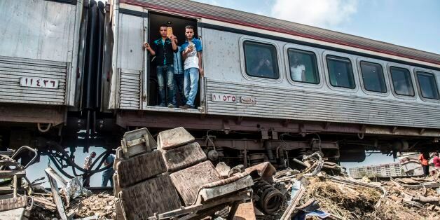 Passengers on an incoming train, which slowed down at the scene of a fatal rail collision the day before, use their cell-phones to take snaps of the outlying wreckage by the tracks in the area of Khorshid on the outskirts of Egypt's Mediterranean city of Alexandria from the day before, on August 12, 2017.The toll from the accident on August 11, 2017, when two trains hurtled into each other near Egypt's second-largest city, has risen to 40 dead and 123 wounded, said health ministry spokesman Khaled Moujahed, as local media said the number of fatalities was likely to rise. / AFP PHOTO / KHALED DESOUKI (Photo credit should read KHALED DESOUKI/AFP/Getty Images)