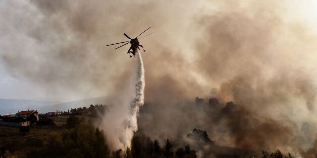A firefighting helicopter drops water on a fire burning east of the Greek capital Athens on August 15, 2017.The army was called in to assist firefighters around Kalamos, 45 kilometres (30 miles) east of Athens, where a fire has been burning since August 13. In all, 146 fires have broken out across Greece since then according to authorities. / AFP PHOTO / ARIS MESSINIS (Photo credit should read ARIS MESSINIS/AFP/Getty Images)