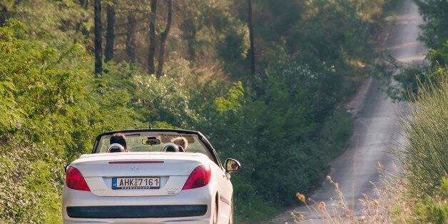 Kassandra, Greece - August 14, 2014: Cuople riding in Peugeot 207 CC on a curvy road.