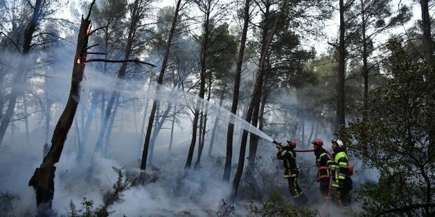 Firefighters work to extinguish a fire in Port-de-Bouc, southeastern France on August 10, 2017. Dry conditions fuelled a wildfire on France's Mediterranean coast. About 200 firefighters backed by six water-dropping aircraft battled a blaze in Port-de-Bouc west of Marseille which was threatening built up areas, local firefighters said. / AFP PHOTO / BERTRAND LANGLOIS (Photo credit should read BERTRAND LANGLOIS/AFP/Getty Images)