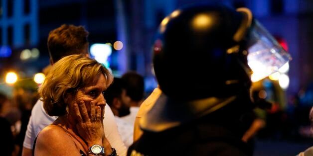 A woman gestures as she is escorted out by Spanish policemen outside a cordoned off area after a van ploughed into the crowd, killing 13 persons and injuring over 80 on the Rambla in Barcelona on August 17, 2017.A driver deliberately rammed a van into a crowd on Barcelona's most popular street on August 17, 2017 killing at least 13 people before fleeing to a nearby bar, police said. Officers in Spain's second-largest city said the ramming on Las Ramblas was a 'terrorist attack'. / AFP PHOTO / PAU BARRENA (Photo credit should read PAU BARRENA/AFP/Getty Images)