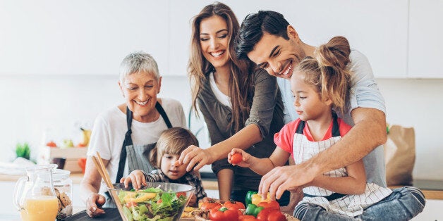 Three-generation family with two small children preparing food.