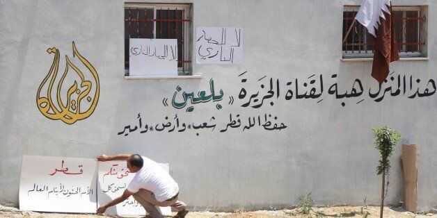 RAMALLAH, WEST BANK - JULY 2: A Palestinian man places placards to the wall of a house after Palestinian farmer Ayid Burnat donates his house to Doha-based Al Jazeera Television to show solidarity with Qatar due to political and economic embargo applied by Saudi-led Arabic countries, at Belin district of Ramallah, West Bank on July 2, 2017. (Photo by Issam Rimawi/Anadolu Agency/Getty Images)
