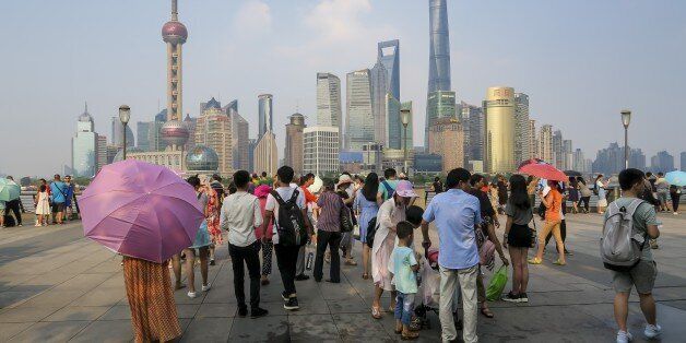 People walk on the waterfront bund in Shanghai on July 21, 2017.Shanghai sweltered under a new record high of 40.9 degrees Centigrade (105 F) on July 21, authorities said as they issued a weather 'red alert' over a stubborn heat wave that has plagued much of the country. / AFP PHOTO / STR / China OUT (Photo credit should read STR/AFP/Getty Images)