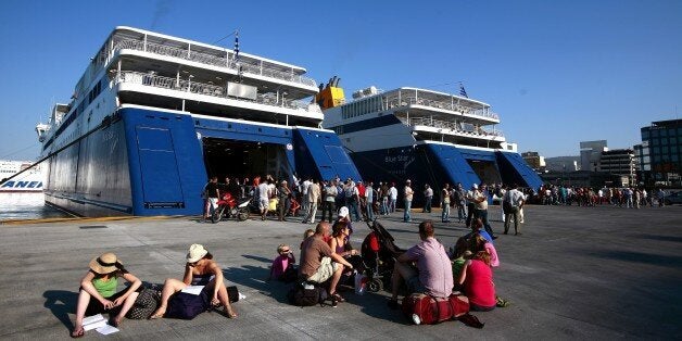 Tourists sit at the port of Piraeus on June 28, 2011 as around 200 militants of communist-affiliated unions prevent ferries from leaving the harbor during a 48-hour general strike. Greece ground to a halt on June 28 as a 48-hour general strike began to bite against the bankruptcy-threatened government which is desperately trying to push through sweeping austerity cuts. As parliament votes on the drastic belt-tightening measures to unlock 12 billion euros (17 billion US dollars) of blocked funds from the EU and IMF, unions have called on Greeks facing hefty tax hikes to stage mass demonstrations. AFP PHOTO / Alkis Konstantinidis (Photo credit should read Alkis Konstantinidis/AFP/Getty Images)