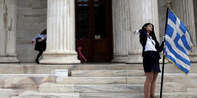 Children (L) play hide and seek as a student holds a Greek national flag at the entrance of the Athens Academy, following a student parade marking the