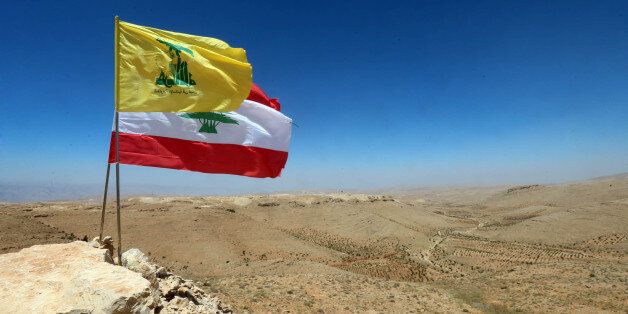 The national flag of Lebanon and the flag of Lebanese Shiite movement Hezbollah are seen placed amidst rocks during a press tour organised by Hezbollah in a mountainous area around the Lebanese border town of Arsal on July 25, 2017.Lebanese movement Hezbollah said its fight against militant groups along the eastern border with war-ravaged Syria was 'nearing its end', and called on fighters to surrender. / AFP PHOTO / STRINGER (Photo credit should read STRINGER/AFP/Getty Images)