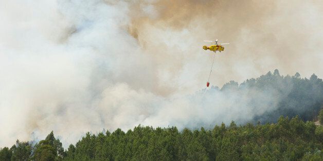 CASAL DE SÃ£O JOÃ£O, COJA, ARGANIL, PORTUGAL - 2017/06/08: A Russian-built Kamov KA-32 firefighting helicopter drops water on a forest fire above the small village hamlet of Casal de SÃ£o JoÃ£o. Portugal is enduring a severe drought and forest fires are springing up in many areas, either from natural causes such as thunderstorms or, as some are claiming, from arson. (Photo by Peter Charlesworth/LightRocket via Getty Images)