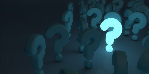 bright blue glowing question mark stands out in the dark amongst other question mark symbols