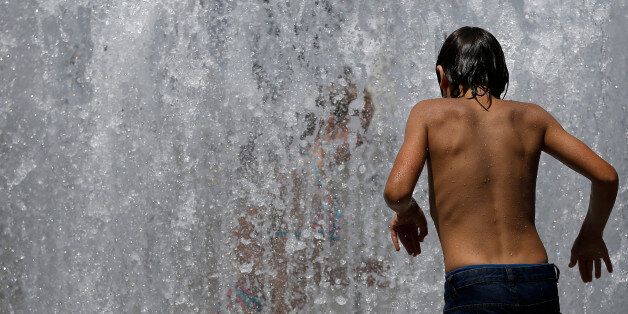 A child plays in a fountain of water to cool off from the heat in Nantes as unusually high temperatures hit France, June 21, 2017. REUTERS/Stephane Mahe