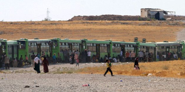 Syrian refugees and militants evacuated from northeastern Lebanon are seen just before crossing into the rebel-held area of Al-Saan in the central Hama province on August 3, 2017. Thousands of Syrian refugees were bussed out of the restive border area between Lebanon and Syria as part of a ceasefire deal between Lebanon's Shiite movement Hezbollah and fighters from Al-Qaeda's former Syrian branch. In exchange, the jihadist group released two Hezbollah fighters, an AFP correspondent said, adding that they arrived in Red Crescent vehicles in the area of Al-Saan in central Hama province. / AFP PHOTO / George OURFALIAN (Photo credit should read GEORGE OURFALIAN/AFP/Getty Images)