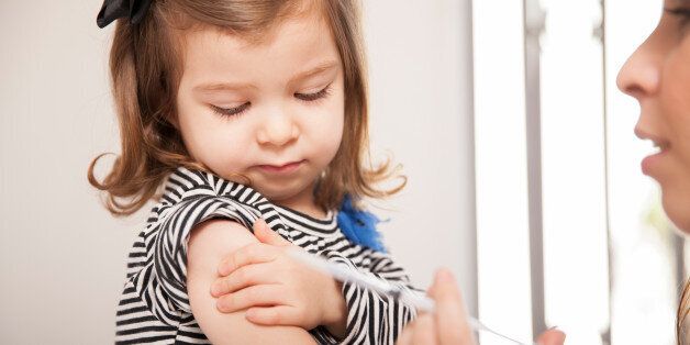 Closeup of a cute little girl getting a flu shot at a doctor's office