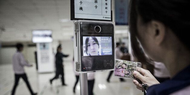 An employee uses a facial recognition device as she swipes her badge to enter the assembly line area at a Pegatron Corp. factory in Shanghai, China, on Friday, April 15, 2016. This is the realm in which the world's most profitable smartphones are made, part of Apple Inc.'s closely guarded supply chain. Photographer: Qilai Shen/Bloomberg via Getty Images
