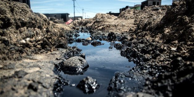 QAYYARAH, IRAQ - APRIL 10: A pool of oil lies at the site of an extinguished oil fire that was started by retreating Islamic State fighters at the beginning of the Mosul offensive, on April 10, 2017 in Qayyarah, Iraq. The refinery and oil fields at Qayyarah were set ablaze by retreating Islamic State fighters during the battle to retake Mosul and have left a legacy of environmental damage and health risks that will pose dangers to people in the area for years to come. Oil is believed to have seeped into the Tigris river to pollute local water supplies and the potentially toxic remains of destroyed buildings and military equipment also present long-term threats to people in the region. (Photo by Carl Court/Getty Images)