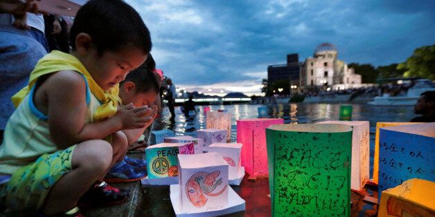 Children pray after releasing paper lanterns on the Motoyasu river facing the Atomic Bomb Dome in remembrance of atomic bomb victims on the 72nd anniversary of the bombing of Hiroshima, western Japan, August 6, 2017, in this photo taken by Kyodo. Mandatory credit Kyodo/via REUTERS ATTENTION EDITORS - THIS IMAGE WAS PROVIDED BY A THIRD PARTY. MANDATORY CREDIT. JAPAN OUT. NO COMMERCIAL OR EDITORIAL SALES IN JAPAN.