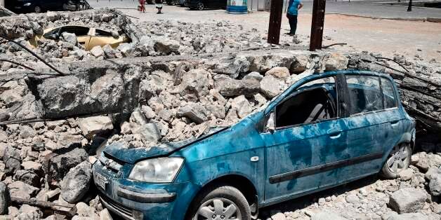 A man looks at cars under rubble on the Kos island on July 22, 2017, following an earthquake which struck the region. Two foreigners died and more than 100 people were injured on the Greek island of Kos when an earthquake shook popular Greek and Turkish holiday destinations in the Aegean Sea. The epicentre of the 6.7 magnitude quake was some 10.3 kilometres (6.4 miles) south of the major Turkish resort of Bodrum, a magnet for holidaymakers in the summer, and 16.2 kilometres east of the island of Kos in Greece, the US Geological Survey sai . / AFP PHOTO / LOUISA GOULIAMAKI (Photo credit should read LOUISA GOULIAMAKI/AFP/Getty Images)