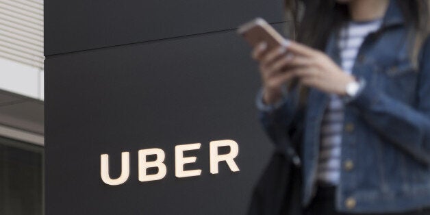 A pedestrian checks a mobile device in front of the Uber Technologies Inc. headquarters building in San Francisco, California, U.S., on Wednesday, June 21, 2017. Travis KalanickÂ has resigned from his job leadingÂ Uber Technologies Inc., giving up his effort to hold onto power as a torrent of self-inflicted scandals enveloped him and the global ride-hailing leviathan he co-founded. Photographer: David Paul Morris/Bloomberg via Getty Images