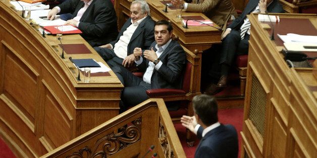 Greek PM Alexis Tsipras (C) gestures listening main opposition leader Kyriakos Mitsotakis delivering a speech on the podium, during a debate on education in the Greek Parliament, in Athens on September 28 , 2016 (Photo by Panayiotis Tzamaros/NurPhoto via Getty Images)
