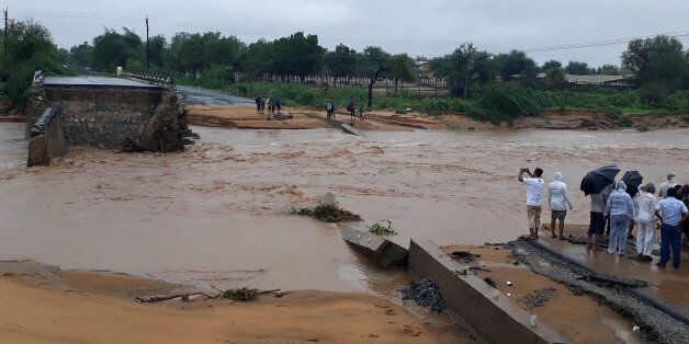This photo taken on July 25, 2017 shows people gathering next to a washed away road in Deesa municipality, which has been hit by severe flooding along the Banas River in northern Gujarat state in western India.Indian rescue crews were working on July 26 to save flood victims and recover bodies in communities devastated by heavy monsoon flooding. The official death toll from the floods in the westernmost state stands at 111, with more than 36,000 people evacuated to safe areas as helicopters and boats try to reach those still stranded. / AFP PHOTO / STR (Photo credit should read STR/AFP/Getty Images)