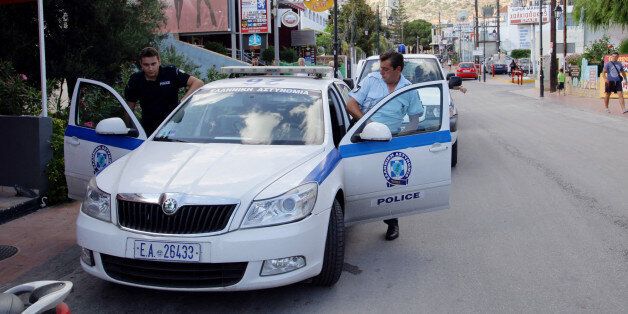 Policemen enter their vehicle on July 23, 2013 in Malia on the Greek island of Crete, outside the place where a 19-year-old British tourist was found dead in front of a closed bar after being stabbed in the chest. Another Briton tourist of the same age was arrested today on suspicion of the crime and another 17 people, all Britons, have been taken into custody in connection with the incident. AFP PHOTO / Costas Metaxakis (Photo credit should read Costas Metaxakis/AFP/Getty Images)
