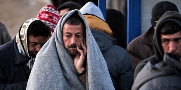 A man with a blanket over his head to protect from the morning cold waits with other migrants and refugess to register at a makeshift camp at the Greek-Macedonian border near the Greek village of Idomeni, on March 5, 2016, where thousands of refugees and migrants wait to cross the border into Macedonia.EU president Donald Tusk struck an unusually upbeat note on the migrant crisis on March 4 as Turkey raised the possibility of taking back non-Syrian asylum seekers. / AFP / LOUISA GOULIAMAKI (Photo credit should read LOUISA GOULIAMAKI/AFP/Getty Images)
