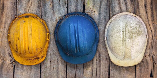 Three vintage construction helmets hanging on an old wooden wall