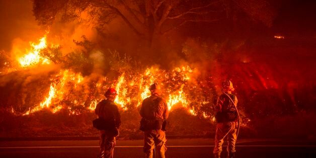 Firefighters monitor flames on the side of a road as the Detwiler fire rages on near the town of Mariposa, California on July 18, 2017.California has suffered widespread fires in recent days, with a lighting strike near Yosemite National Park sparking a blaze that destroyed more than 26 square kilometers (10 square miles) of forest. / AFP PHOTO / JOSH EDELSON (Photo credit should read JOSH EDELSON/AFP/Getty Images)