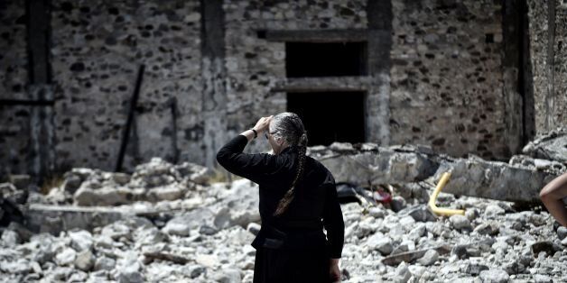 A woman looks at quake-damaged buildings on the Greek Island of Kos on July 22, 2017 , a day after a 6.5 magnitude earthquake struck the region. The Greek holiday island of Kos was struggling to recover from a 6.7-magnitude earthquake that killed two people and injured hundreds more, battling flight delays and a harbour knocked out for a second day. / AFP PHOTO / LOUISA GOULIAMAKI (Photo credit should read LOUISA GOULIAMAKI/AFP/Getty Images)