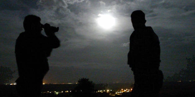 KIPI, GREECE: A Greek border guard scans the Evros river with a pair of night vision binoculars on the look out for illegal immigrants, near Kipi village in northeastern greece on the border with Turkey, 13 October 2003. The river lies along a major route for people-smuggling from Asia to Europe and more than 10,000 illegal immigrants were arrested on the Greek side in 2002. AFP PHOTO/ FAYEZ NURELDINE (Photo credit should read FAYEZ NURELDINE/AFP/Getty Images)