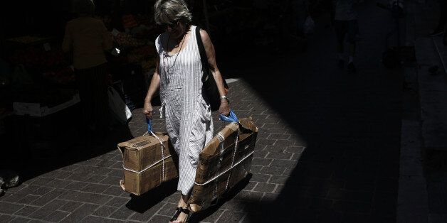 A pedestrian carries packages outside the central meat and fish market in Athens, Greece, on Tuesday, June 13, 2017. Prime minister Alexis Tsipras has spent nearly two years telling Greeks that a debt deal and inclusion in the European Central Banks quantitative-easing program will unleash an investment boom that salves the pain of austerity. Photographer: Kostas Tsironis/Bloomberg via Getty Images