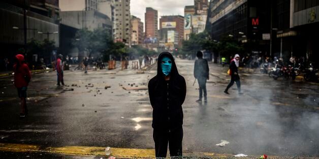 An masked opposition activist takes part in a blockade to protest against Venezuelan President Nicolas Maduro in Caracas, on July 19, 2017.Venezuela's military chiefs reaffirmed their loyalty to President Nicolas Maduro on Wednesday by saying their forces would protect a controversial vote he has called for next week to elect a body to rewrite the constitution. / AFP PHOTO / RONALDO SCHEMIDT (Photo credit should read RONALDO SCHEMIDT/AFP/Getty Images)