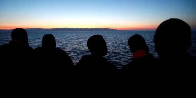Migrants look at south Italy's coast as they approach on the Vos Hestia ship after being rescued by