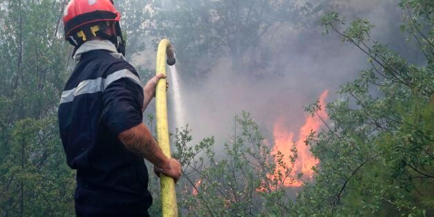 A firefighter uses a hose to spray water as they fight against a fire in Castagniers, near Nice, on July 17, 2017. / AFP PHOTO / Valery HACHE (Photo credit should read VALERY HACHE/AFP/Getty Images)