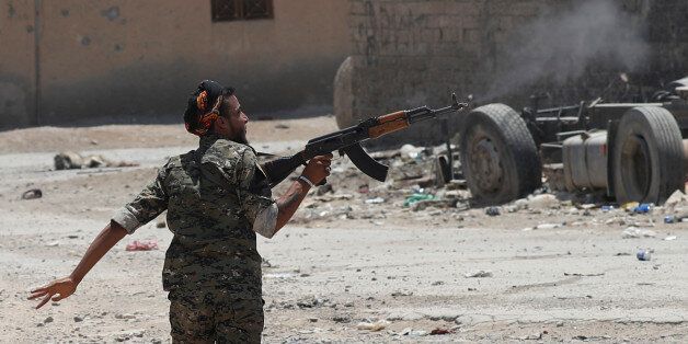 A Kurdish fighter from the People's Protection Units (YPG) fires his rifle at Islamic State militants as he runs across a street in Raqqa, Syria July 3, 2017. REUTERS/Goran Tomasevic