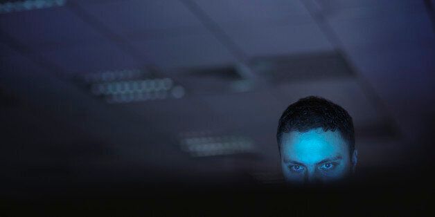 Computer hacker working on laptop late at night in office