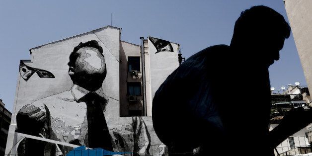 A pedestrian walks past a wall mural by visual artist 'Ino' in Athens, Greece, on Thursday, June 29, 2017. The change in sentiment toward Greece -- the epicenter of the European financial crisis -- is reflected in the fact that countrys bond yields are the lowest since before the turmoil even as the debt remains deep in junk territory. Photographer: Kostas Tsironis/Bloomberg via Getty Images