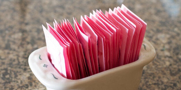 A stoneware container holding packets of artificial sweetener.