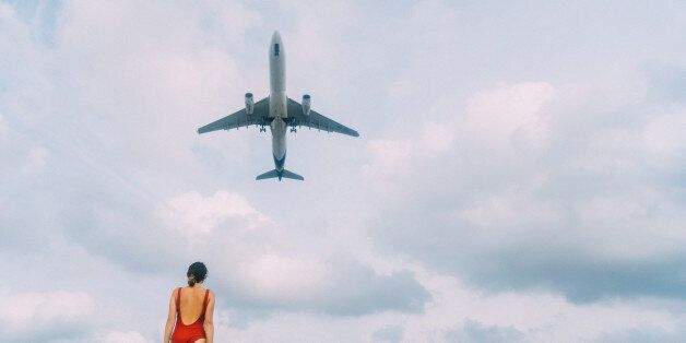 Plane flying above the young caucasian woman on the beach, Thailand