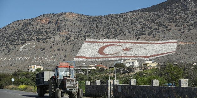TASKENT, CYPRUS - MARCH 06: A tractor in the Turkish Republic of North Cyprus (TRNC) drives by a massive TRNC flag that adorns a mountainside on March 6, 2017 in Taskent, Cyprus. Cyprus has been divided into a Greek south and Turkish north ever since the brief but devastating war of 1974. Since then United Nations peacekeepers have maintained a buffer zone that runs through the capital city of Nicosia and across the entire island to keep the factions apart. In the south the Greek-dominated Republic of Cyprus is internationally-recognized and a member of the European Union, while in the north the self-proclaimed Turkish Republic of North Cyprus (TRNC) is recognized only by Turkey, which also has tens of thousands of troops stationed there. Negotiations over possible reunification have made strident progress over the last few years, though they have stalled in recent months. (Photo by Sean Gallup/Getty Images)