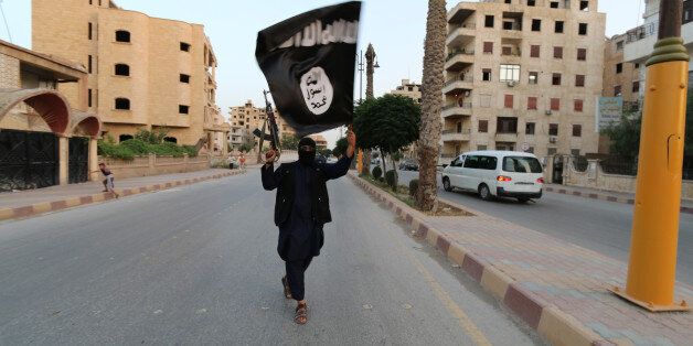 A member loyal to the Islamic State in Iraq and the Levant (ISIL) waves an ISIL flag in Raqqa June 29, 2014. The offshoot of al Qaeda which has captured swathes of territory in Iraq and Syria has declared itself an Islamic