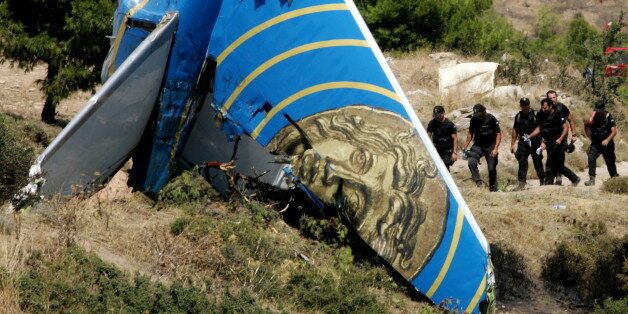 Members of the Greek police elite force walk past a tail of the Cypriot Helios airliner that crashed at Grammatiko village, some 40 km (25 miles) northeast of Athens, August 15, 2005. A Cypriot airliner that crashed in Greece may already have been a flying tomb when it plunged to earth with some of the 121 people aboard already either dead or unconscious, early indications suggest.