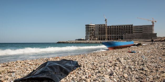 A body of a drowned immigrant is seen covered in plastic after it washed ashore in the Andalus district of the capital Tripoli, on January 4, 2017.After several days at sea 80 mostly Senegalese migrants who left Sabratha on a boat spotted land, thinking it was Italy. Several drowned trying to swim to shore. But when the survivors reached dry land they found they were still in Libya. / AFP / TAHA JAWASHI (Photo credit should read TAHA JAWASHI/AFP/Getty Images)