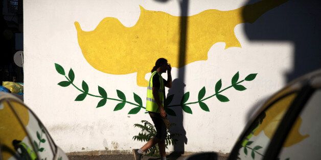 A man walks past a Cypriot flag painted on a wall in Nicosia, Cyprus July 7, 2017. REUTERS/Yiannis Kourtoglou