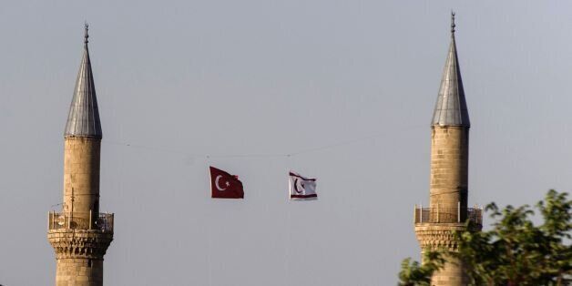 A Greek flag (L) is seen on June 30, 2017 in the foreground as the banner of the breakaway Turkish Republic of Northern Cyprus (R) flutters next to Turkey's flag atop the Suleimiye mosque, a former Roman Catholic cathedral turned into a mosque during the Ottoman rule of Cyprus, on the northern side of Nicosia, the divided capital of the east Mediterranean island. UN Secretary General Antonio Guterres held 'highly constructive' talks on Cyprus with President Nicos Anastasiades, the Greek-Cypriot leader who heads Cyprus's internationally-recognised government, and his Turkish-Cypriot counterpart Mustafa Akinci in Switzerland, enabling a clear vision of what could lead to a settlement, the UN said on July 1, 2017. / AFP PHOTO / Iakovos Hatzistavrou (Photo credit should read IAKOVOS HATZISTAVROU/AFP/Getty Images)