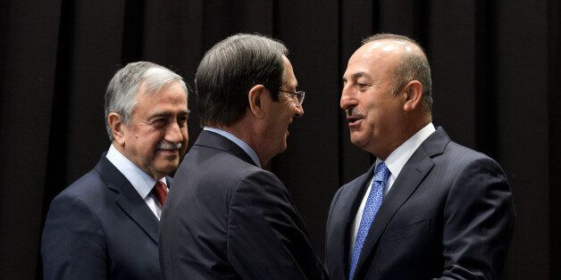 Turkish Foreign Minister Mevlut Cavusoglu (R) greets Greek Cypriot President Nicos Anastasiades (C) next to Turkish Cypriot Leader Mustafa Akinci (L) during peace talks in the Swiss resort of Crans-Montana on June 30, 2017.More than 40 years after Turkish troops invaded northern Cyprus, the presence of tens of thousands of soldiers on the Mediterranean island still looms large over make-or-break peace negotiations this week. / AFP PHOTO / Fabrice COFFRINI (Photo credit should read FABRICE COFFRINI/AFP/Getty Images)