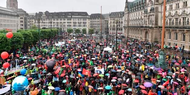 Participants hold placards during a demonstration in front of the Hamburg city hall (Rathaus) called by several NGOs ahead of the G20 summit in Hamburg on a rainy July 2, 2017. / AFP PHOTO / John MACDOUGALL (Photo credit should read JOHN MACDOUGALL/AFP/Getty Images)