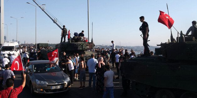 ISTANBUL, TURKEY - JULY 16: People gather for celebration around Turkish police officers, loyal to the government, standing atop tanks abandoned by Turkish army officers, against a backdrop of Istanbul's iconic Bosporus Bridge in Istanbul, July 16, 2016, Turkey. Istanbul's bridges across the Bosphorus, the strait separating the European and Asian sides of the city, had been closed to traffic.Turkish President Recep Tayyip Erdogan has denounced an army coup attempt, that has left atleast 90 dead 1154 injured in overnight clashes in Istanbul and Ankara. (Photo by Burak Kara/Getty Images)