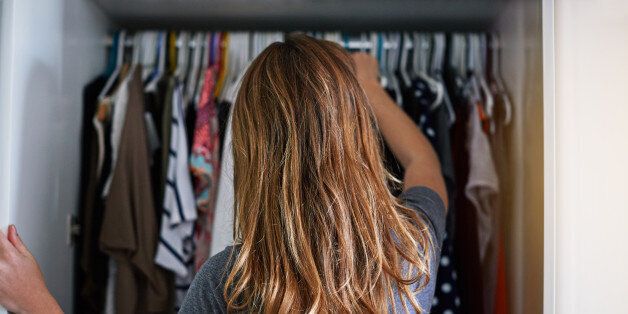 Rearview shot of a young woman standing in front of her closet choosing something to wear